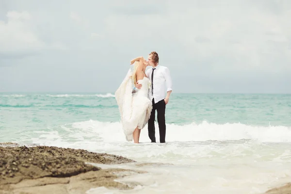 Νύφη και γαμπρός φιλάει στη θάλασσα. ζευγάρι στην αγάπη στην ερημική παραλία. — Φωτογραφία Αρχείου