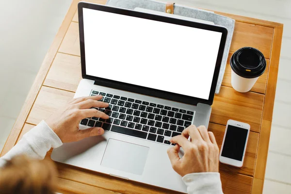 Man typing on laptop at table. Cup of coffee and smartphone