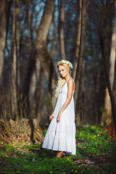 Mulher loira fica em vestido branco por árvore fina . — Fotografia de Stock