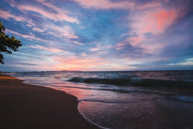 pembe günbatımı sahilde. Plaj dalgalar alacakaranlıkta ile.