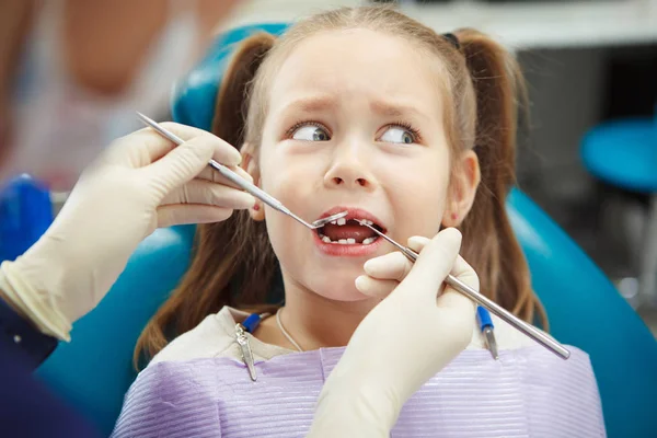 Scared child sits at dentist chair with open mouth Royalty Free Stock Photos