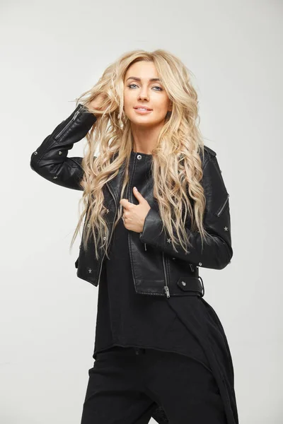 Professioneel model met prachtig blond haar, die zich voordeed op witte achtergrond in een zwart lederen jas. — Stockfoto