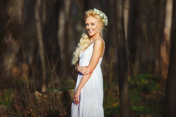 Bela mulher em vestido branco no meio da floresta de primavera . — Fotografia de Stock
