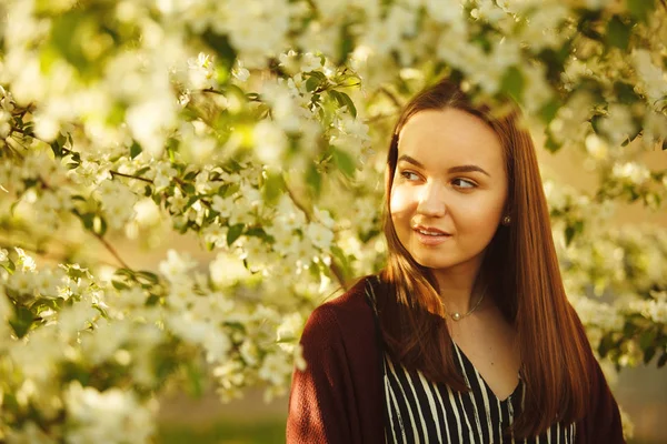 Jovem com pele limpa perto de uma macieira florescente. retrato de menina no parque de primavera . — Fotografia de Stock