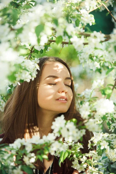 Jovem com pele limpa perto de uma macieira florescente. retrato suave de menina no parque de primavera . — Fotografia de Stock