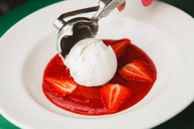 kepçe şeklinde dondurma tabağına koyuyor..