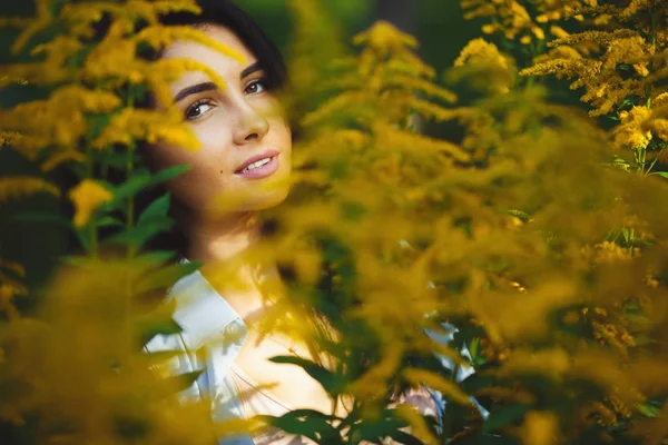 Close-up retrato de mulher morena bonito entre flores amarelas . — Fotografia de Stock