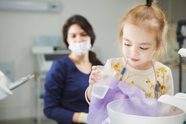 Çocuk ağız durulama ve dişçi koltuğuna oturur