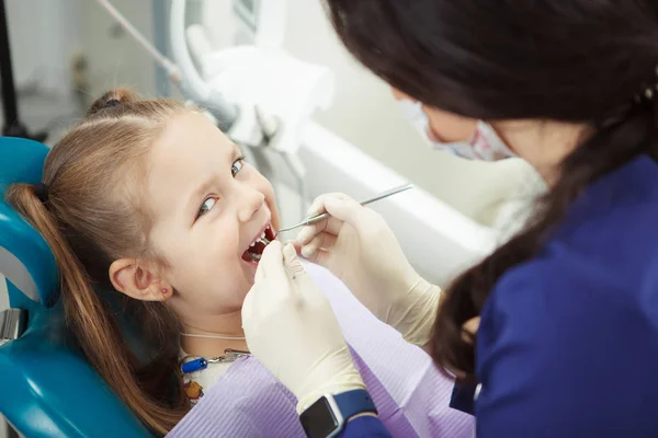Criança está em cadeira de dentista e passa por procedimento — Fotografia de Stock