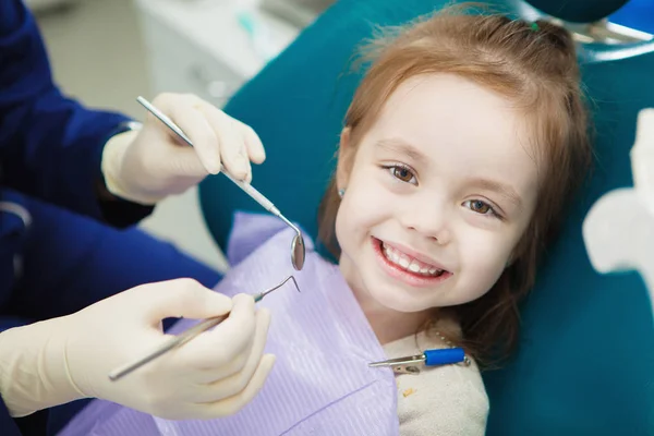 Criança com sorriso bonito senta-se na cadeira do dentista com guardanapo — Fotografia de Stock