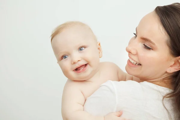 Женщина держит на руках своего очаровательного малыша, улыбающегося ребенка — стоковое фото