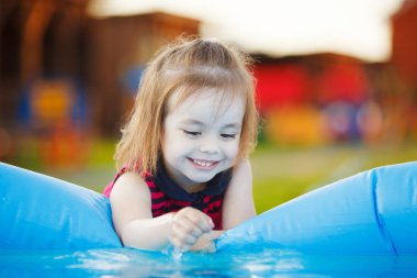 Kız ilgi ile su havuzu dokunur. Deniz kenarında bir meraklı çocuk.