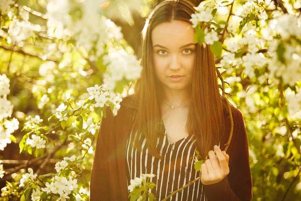 Jovem com pele limpa perto de uma macieira florescente. retrato de menina no parque de primavera . — Fotografia de Stock