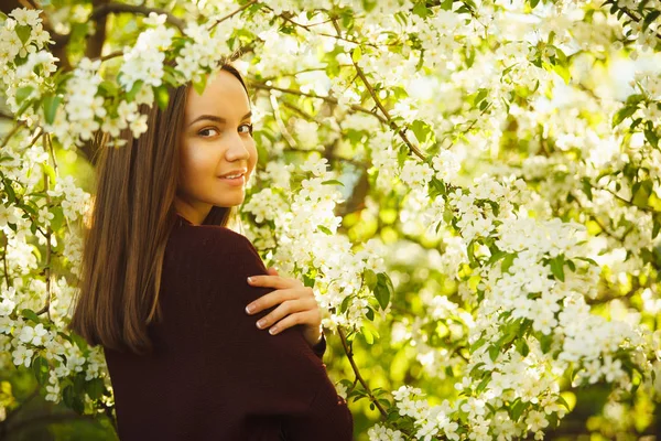 Mujer joven con la piel limpia cerca de un manzano en flor. retrato de niña en el parque de primavera . — Foto de Stock