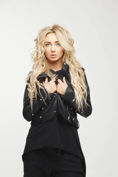 Jeune femme avec de longs cheveux blonds dans des vêtements noirs élégants sur fond blanc . — Photo