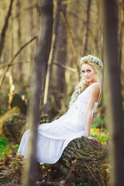 Bela mulher em vestido branco senta-se por árvore floresta verde . — Fotografia de Stock