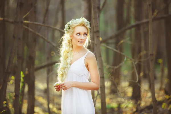白いドレスと春の公園の真ん中に彼女の髪に花輪を捧げる女性. — ストック写真