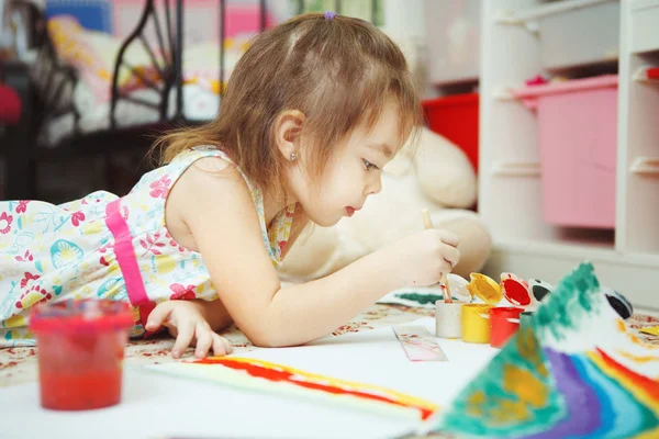 Malá holčička leží na ložnice podlahy a barvy obrázku — Stock fotografie