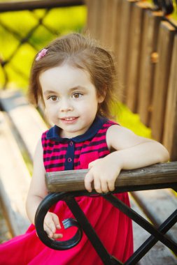 Güzel gözlü kız bankta oturur.