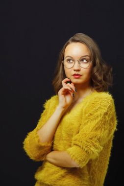 Siyah arka plan üzerinde yukarı doğru seyir düşünceli kız gözlükler, yuvarlak ve parlak giysiler içinde izole portresi.