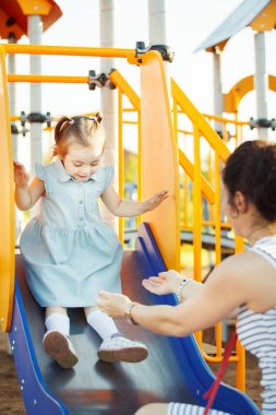 Çocuk tepeden aşağı anneler eller için alır..