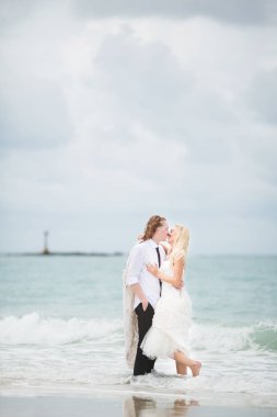 Gelin gelinlik ve denizde sarılma damat. ıssız kumsalda çift tr.