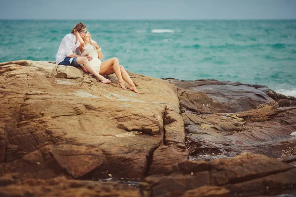 Novia y novio sentado y besándose en la costa rocosa. la pareja recién casada está descansando en Tailandia . —  Fotos de Stock