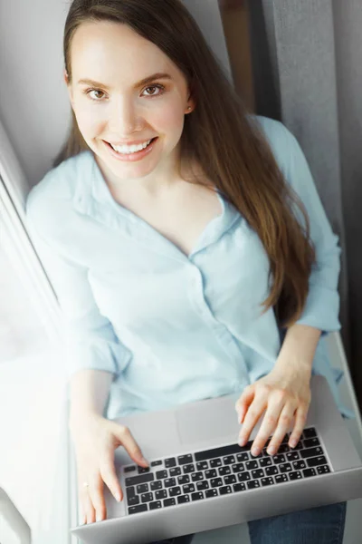 Jovem mulher senta-se com amplo sorriso, laptop no colo — Fotografia de Stock