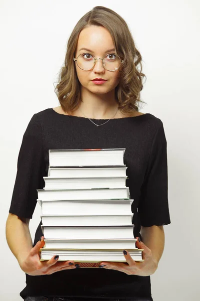 Imagen de mujer sosteniendo muchos libros, llevando gafas redondas y ropa casual, tiene expresión desconcertada, demostrando dificultad o complejidad . — Foto de Stock