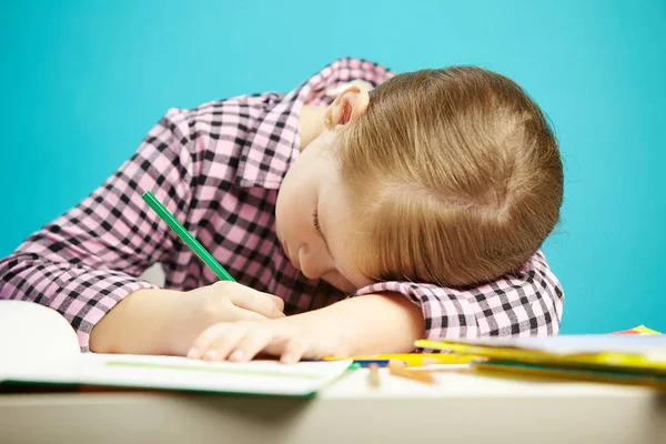 Colpo isolato di bambino con cattiva postura seduto alla scrivania e fare i compiti. Ragazza riposato la testa sul tavolo e scrive nel taccuino . — Foto Stock