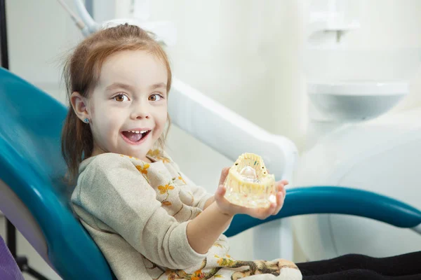 Child plays with artificial human jaw in dentist chair
