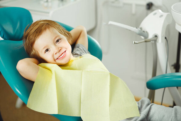 Child in good mood sitting on chair and without fear waiting dentist. Young boy is going to treat teeth. caries, fillings, teeth