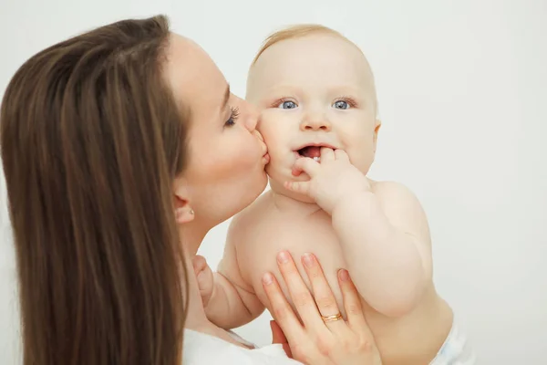 Madre besa a su hijo, el bebé sostiene su dedo cerca de la boca — Foto de Stock