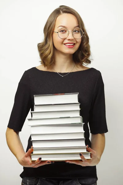 Retrato de mujer atractiva con pila de libros en las manos, tiene expresión feliz, pasó los exámenes al final de la escuela o la universidad, se levanta sobre fondo blanco aislado . — Foto de Stock