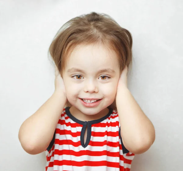 Маленька дівчинка з щирою посмішкою прикриває вуха — стокове фото