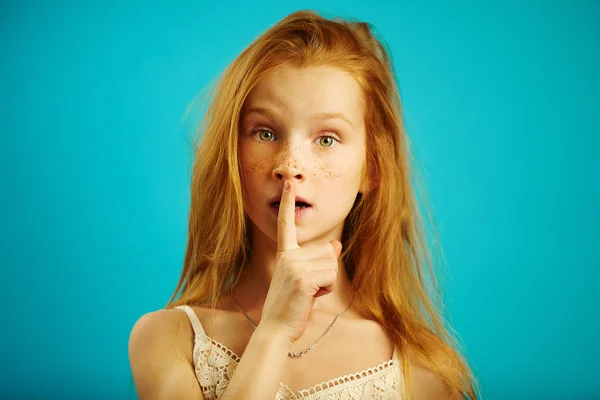 Menina com olhar espantado coloca seu dedo indicador nos lábios, expressa significado de silêncio ou sigilo, demonstra confidencialidade . — Fotografia de Stock