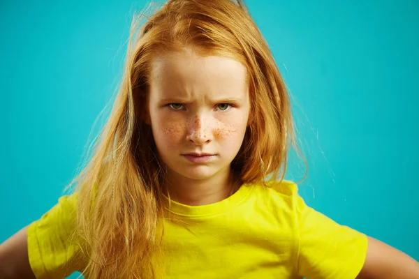 Портрет розчарованої дівчинки з розгромленими бровами, що виражає невдоволення або розбіжності, демонструє труднощі характеру і примхливий настрій, стоїть засмучений дитина на синьому ізольованому . — стокове фото
