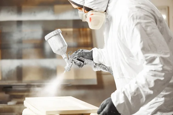 Man i respirator mask måla trä plankor på verkstad. — Stockfoto