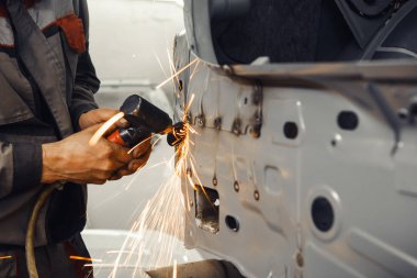 Kaynak temizliği. Kaynak dikişlerinin aşındırıcı bir tekerlek ile pnömatik taşlama makinesinin işlenmesi. Araç gövdesinin onarımı.