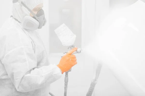 Painting the car in the paint room, spray gun with white paint.