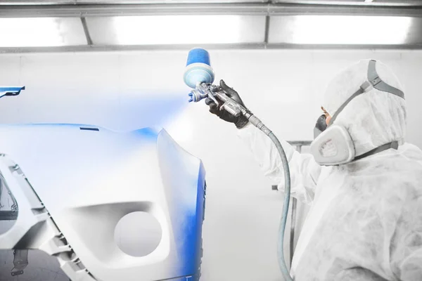 Male worker painting a car bumper in a white paint booth. — Stock Fotó