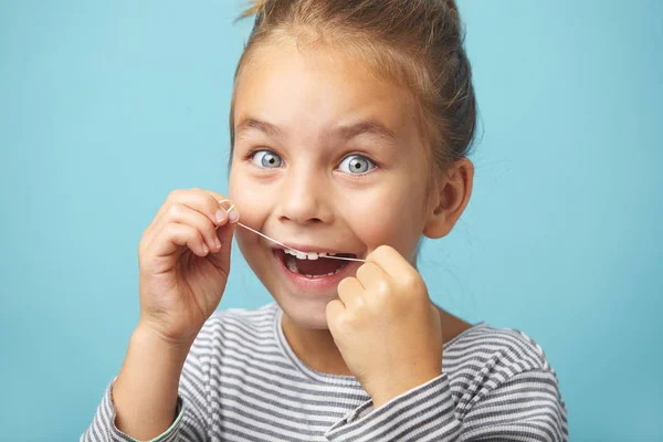 Улыбающаяся девочка использует зубную нить белые здоровые зубы . — стоковое фото