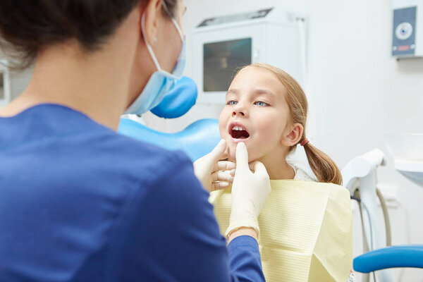 Little cute girl showing a dentist her teeth.