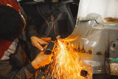 Kaynak dikişlerinin aşındırıcı bir tekerlek ile pnömatik taşlama makinesinin işlenmesi. Kaynak temizliği. Araç gövdesinin onarımı.
