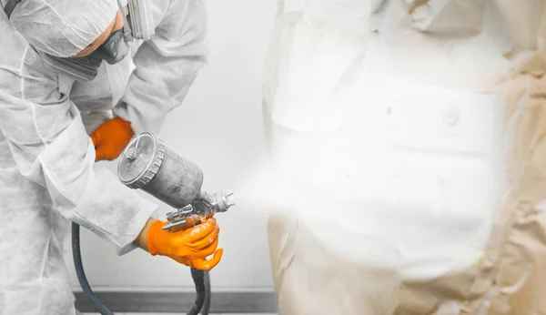 Primer plano de pistola pulverizadora con pintura blanca pintando un coche en cabina pulverizadora . — Foto de Stock