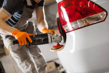 Otomobil tamir atölyesinde orbital cilalayıcısı olan beyaz bir araba, yakın plan. Araç ayrıntıları.