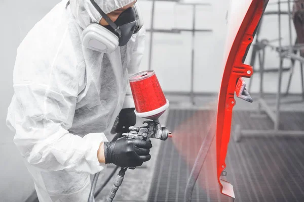 Trabajador mecánico automático pintando la puerta del coche con pistola de pulverización en una cámara de pintura durante los trabajos de reparación . — Foto de Stock