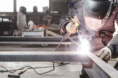 Koruyucu maskeli kaynakçı çelik yapıları kaynaklıyor.