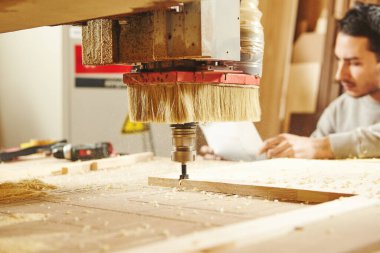 Adam CNC makinesini çizimle karşılaştırıyor. Sayısal denetimli aygıt.