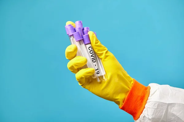 A mão de perto da enfermeira tem tubos de ensaio médicos para o coronavírus. Trabalhador médico em macacões protetores está prestes a tomar um cob em covid-19 . — Fotografia de Stock